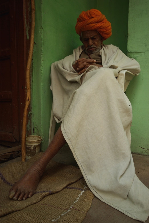 Indian man sleeping in front of his house
