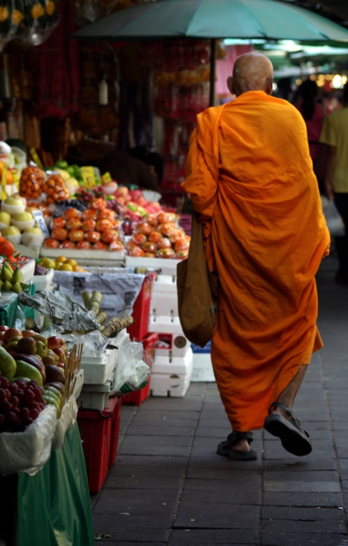 Thailand monk walking among local marketplace